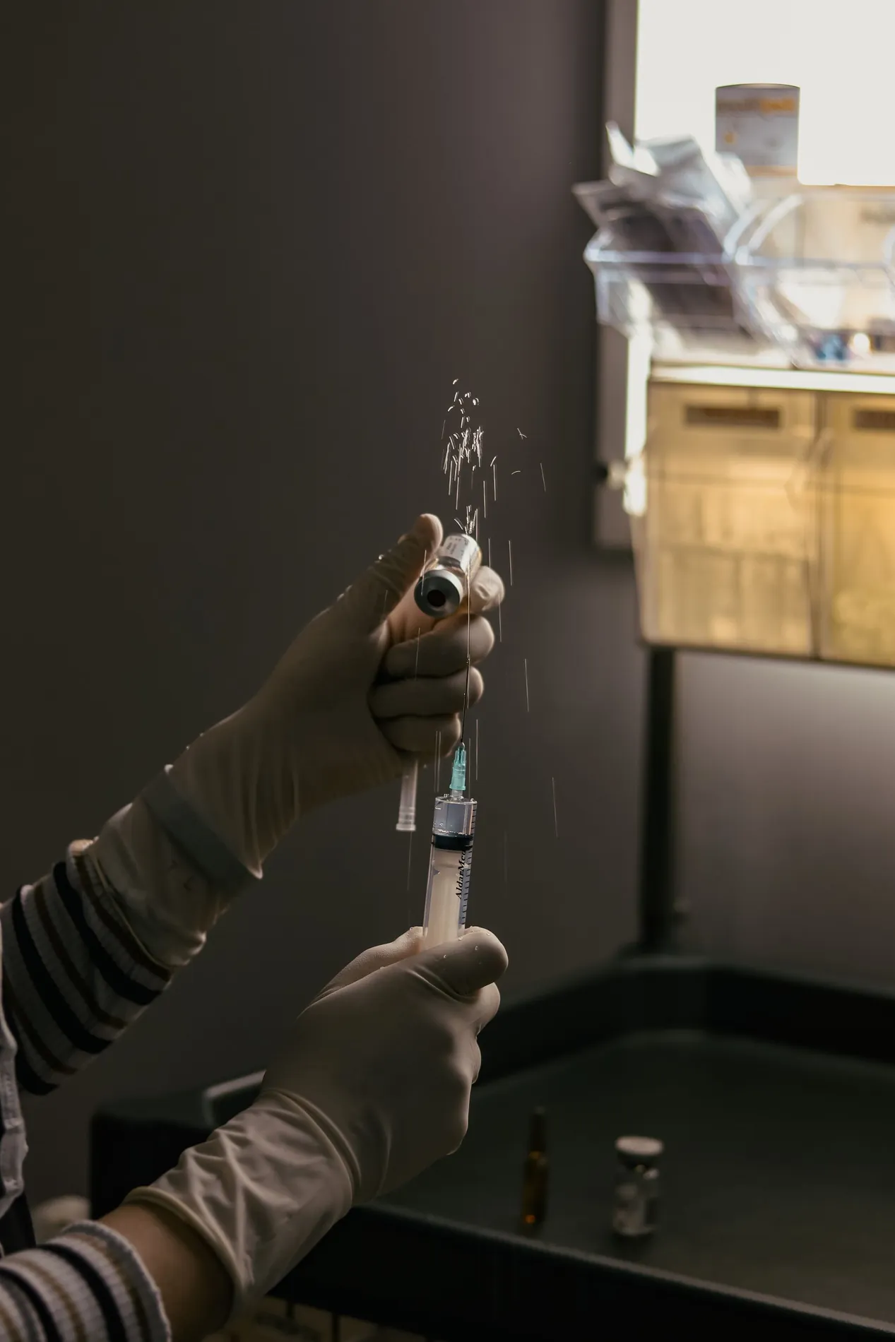 Gloved hands holding two syringes